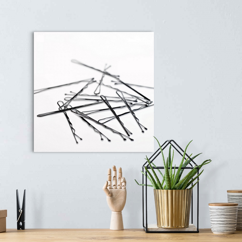 A bohemian room featuring Square, large close up photograph of a small pile of hair pins or bobby pins, on a plain white ba...