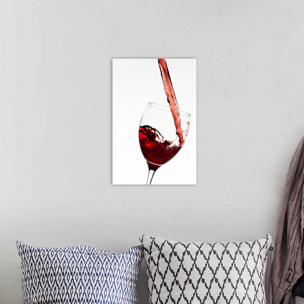 A bohemian room featuring Vertical photograph on a large wall hanging of a stream of red wine as it's poured into a slightl...