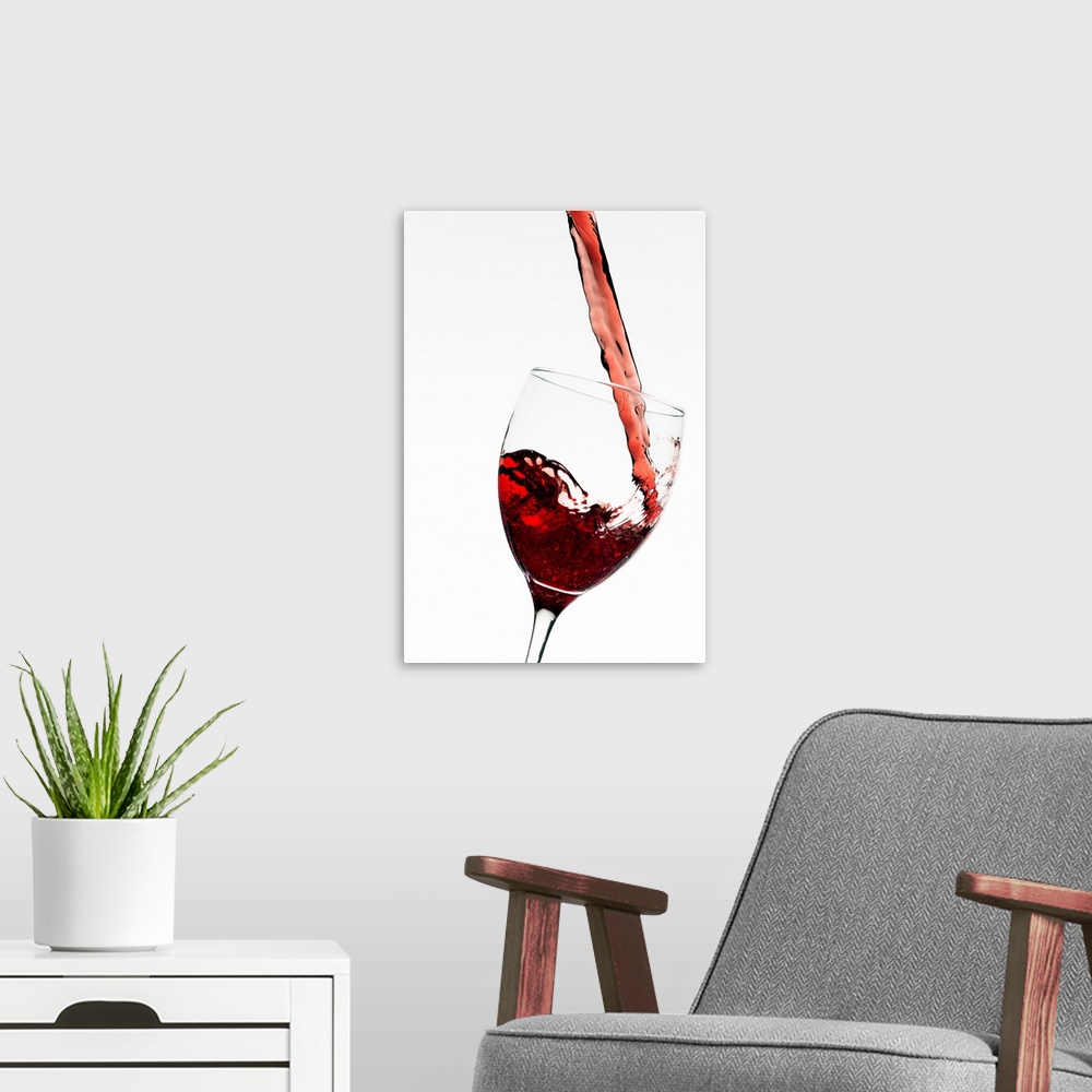 A modern room featuring Vertical photograph on a large wall hanging of a stream of red wine as it's poured into a slightl...