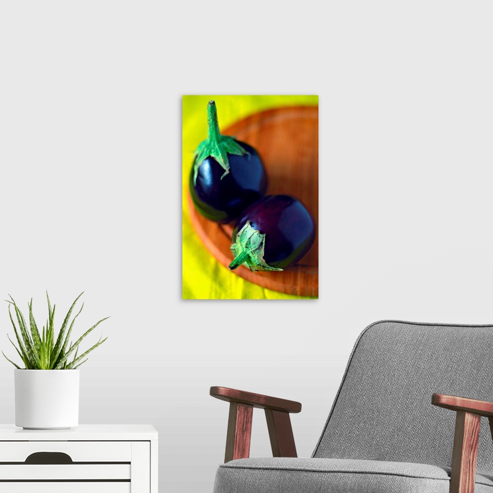 A modern room featuring Close-up of two tiny round eggplants (Solanum melongena) on round wooden chopping board and brigh...