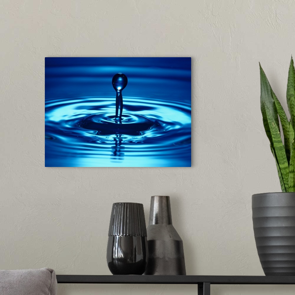 A modern room featuring Macro photograph of a droplet of liquid bouncing up from the water, creating small ripples on the...