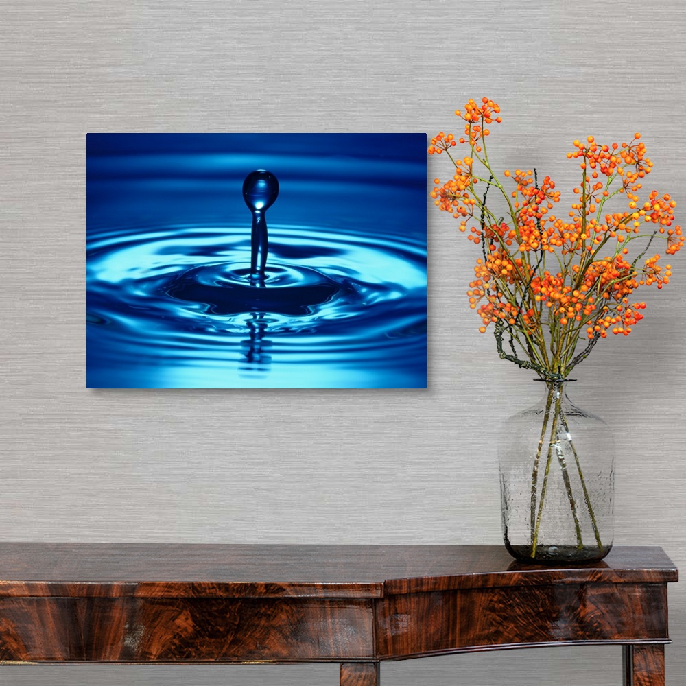 A traditional room featuring Macro photograph of a droplet of liquid bouncing up from the water, creating small ripples on the...
