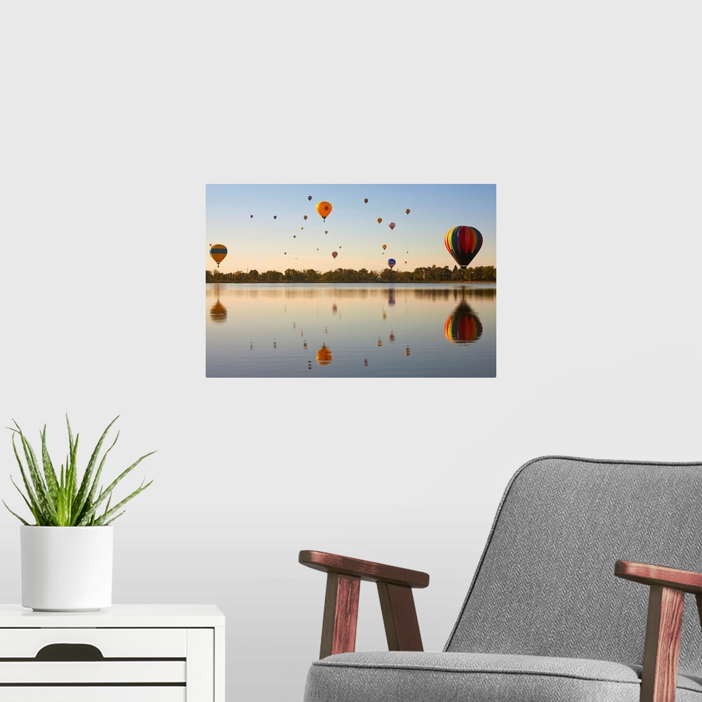 A modern room featuring Colorful air balloons reflected in lake.