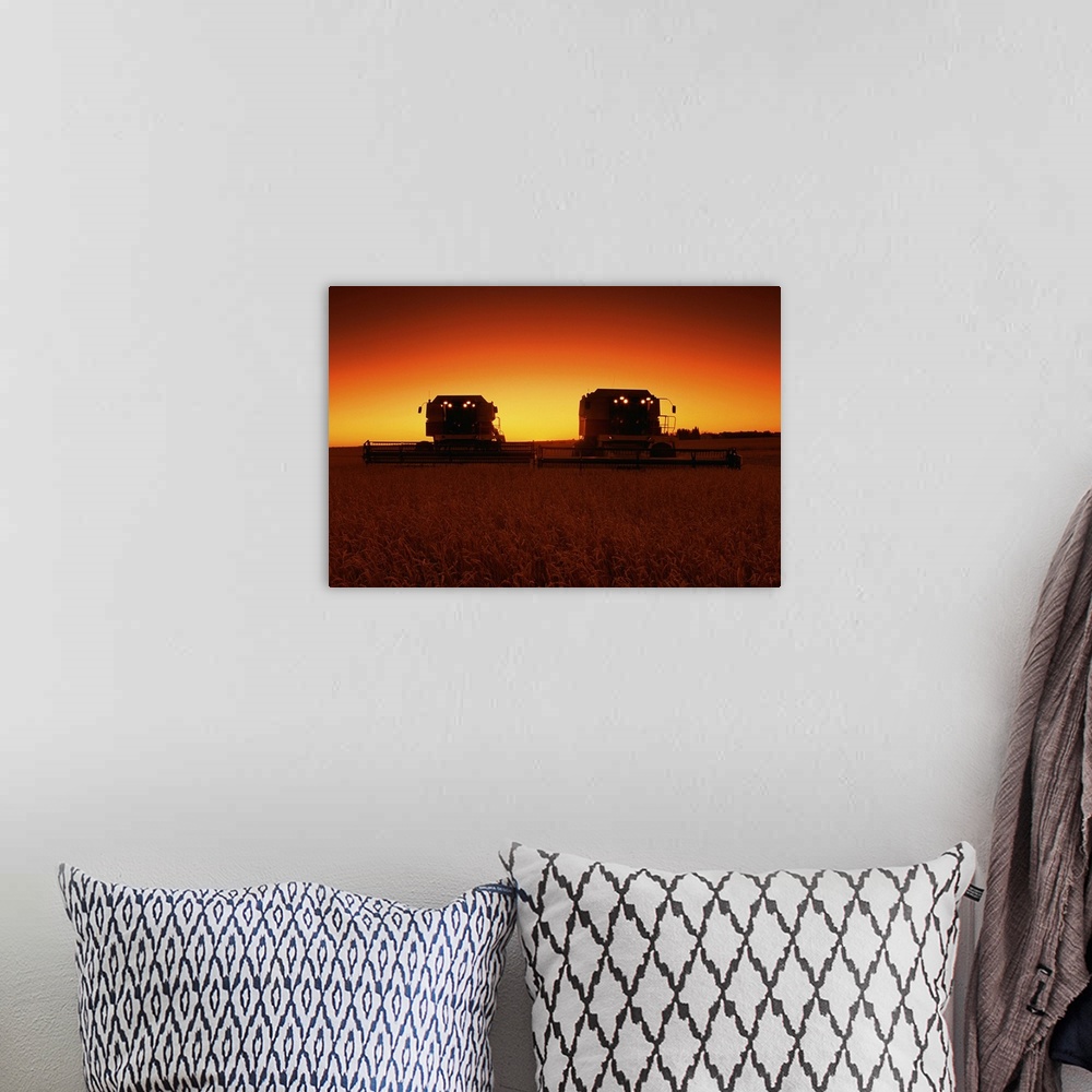 A bohemian room featuring Combines harvesting crop at sunset