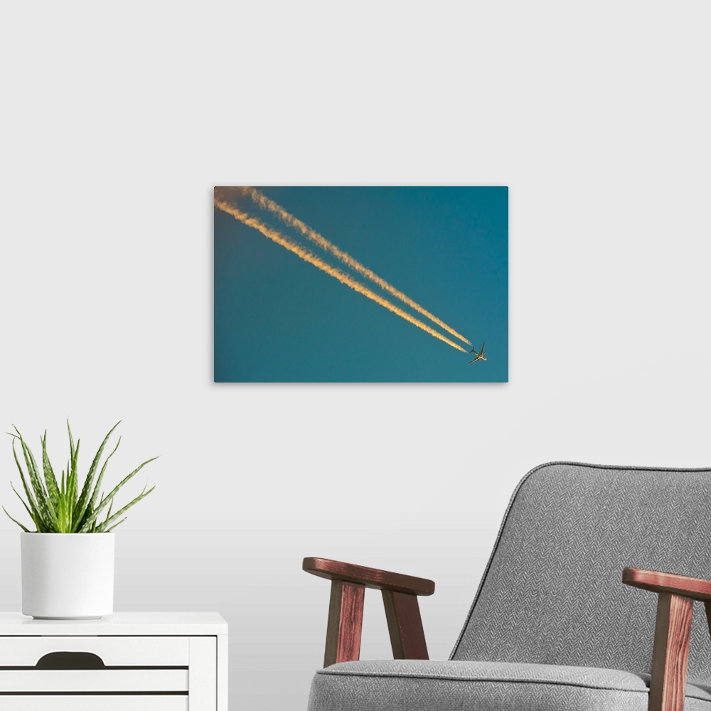 A modern room featuring Long condensation trails in blue sky at sunset.