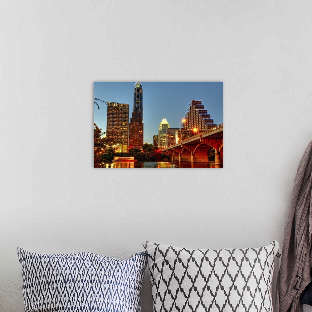 A bohemian room featuring The Austin city skyline is illuminated at dusk in this photograph taken from the river side.