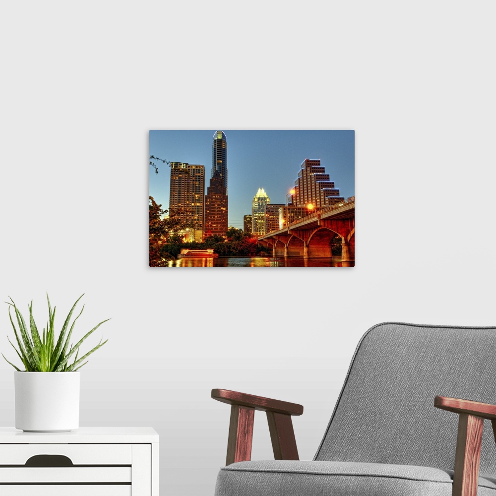 A modern room featuring The Austin city skyline is illuminated at dusk in this photograph taken from the river side.