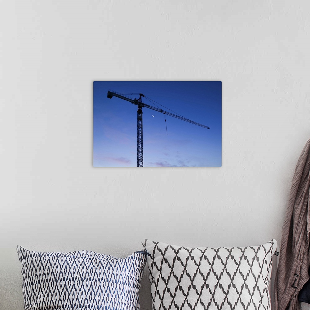 A bohemian room featuring Construction crane silhouetted against a twilight sky.