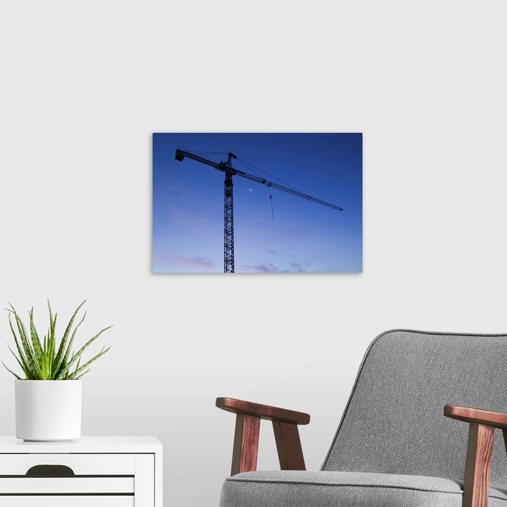 A modern room featuring Construction crane silhouetted against a twilight sky.