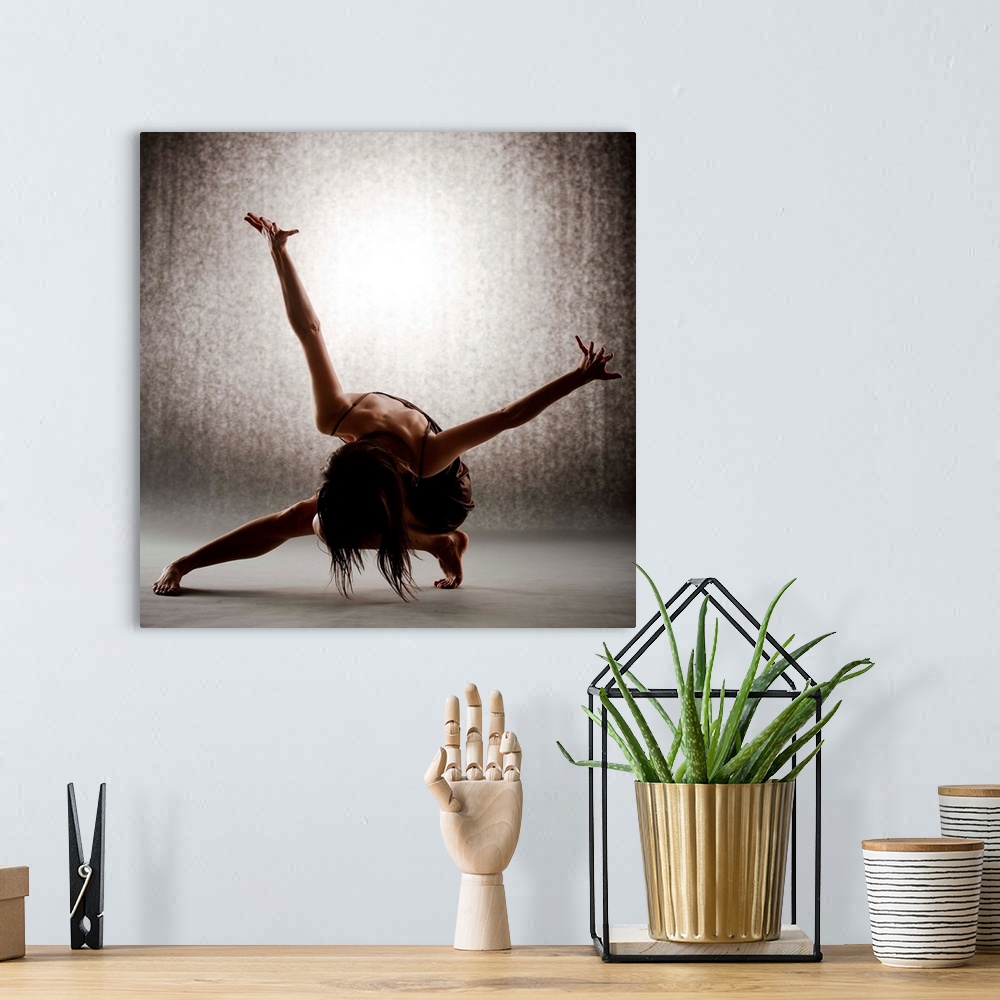 A bohemian room featuring Dancer performing contemporary ballet on grey seamless backdrop wearing brown dress.