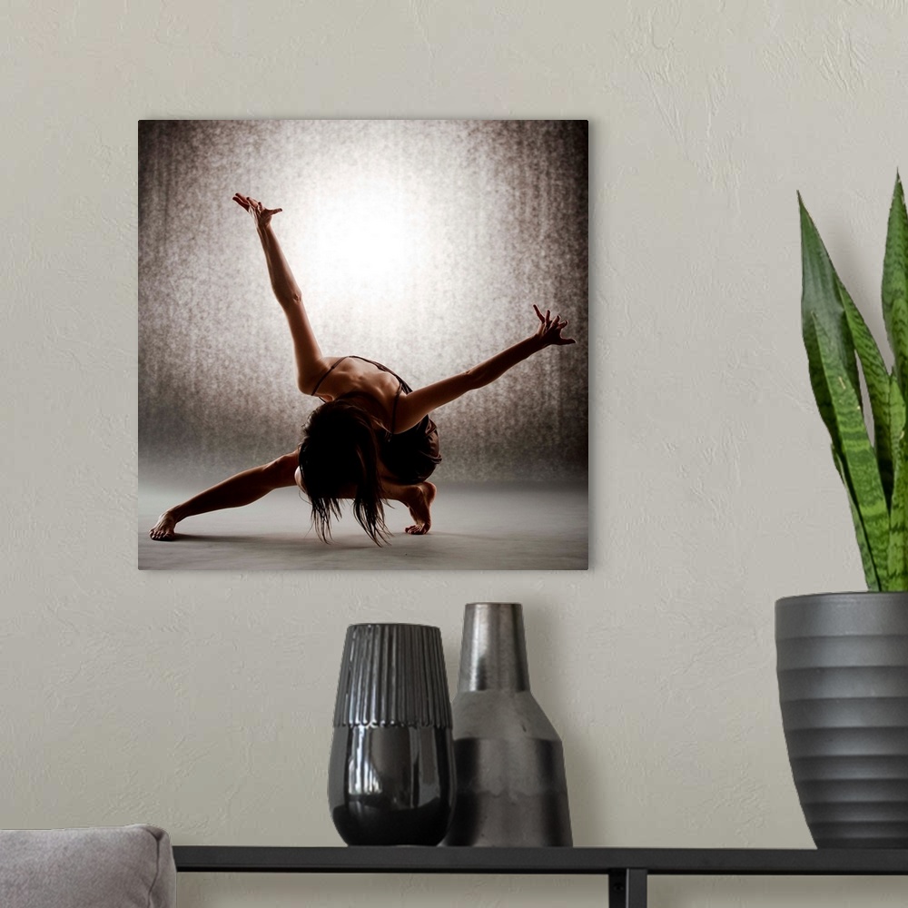 A modern room featuring Dancer performing contemporary ballet on grey seamless backdrop wearing brown dress.