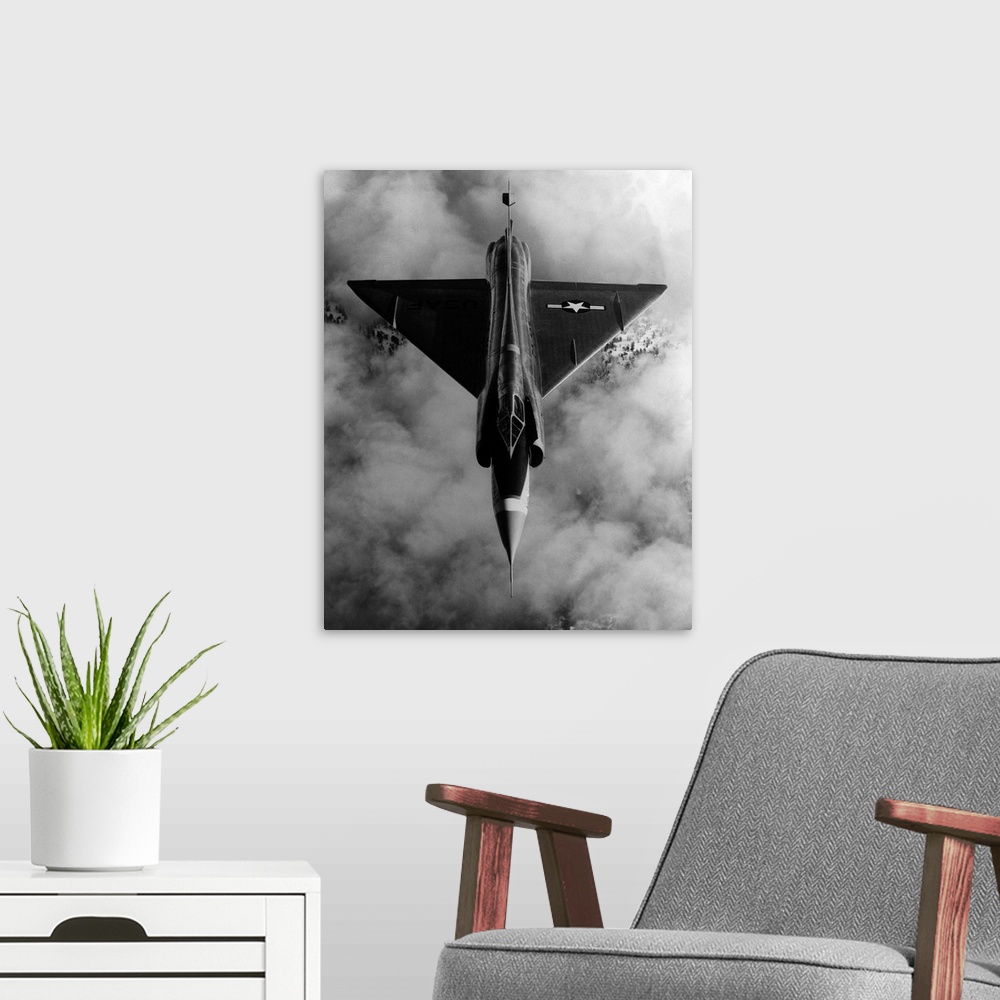 A modern room featuring A United States Air Force, delta-wing F-102A, interceptor aircraft in flight above cloud cover.