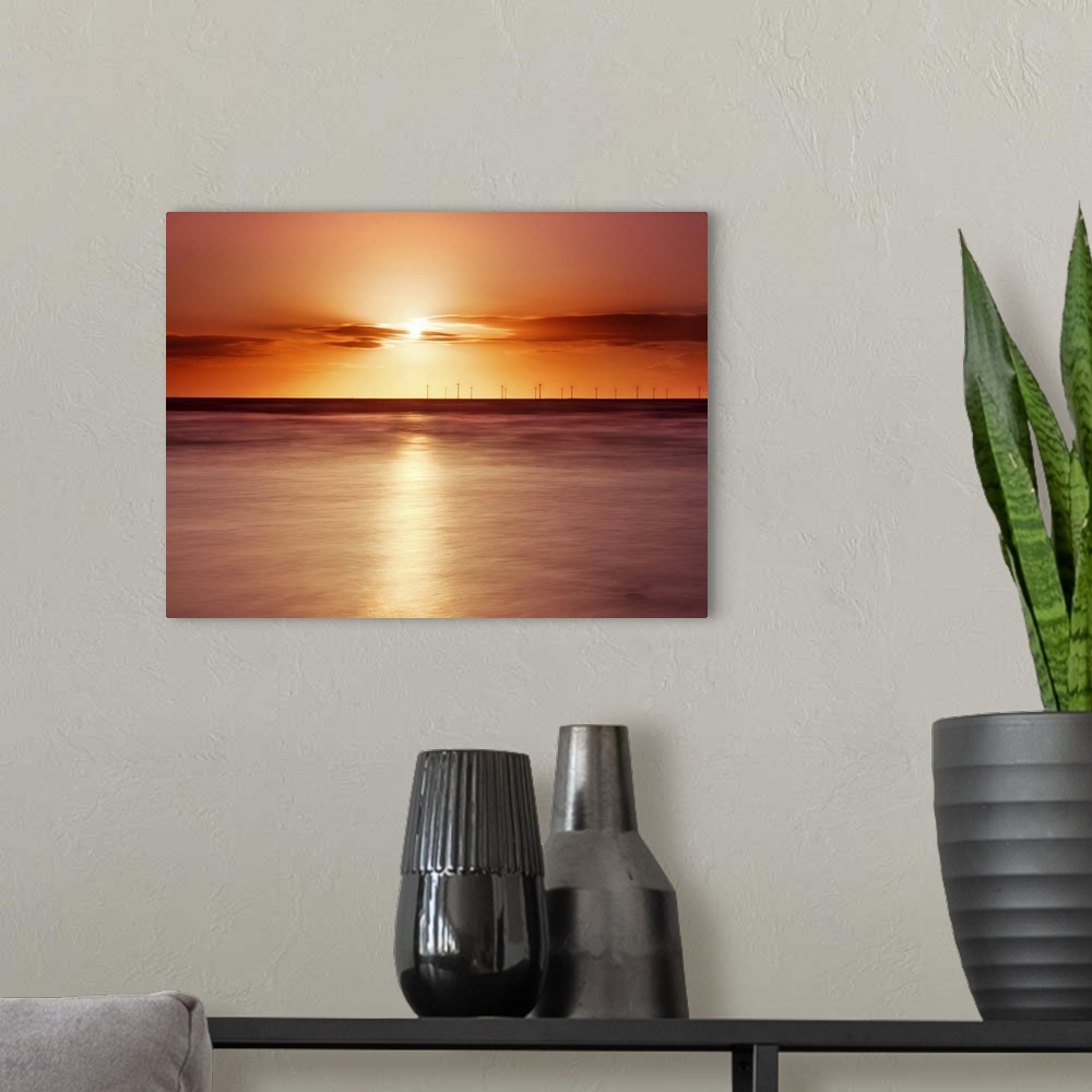 A modern room featuring Crosby beach,golden sunset with windfarm turbines and long exposure sea.