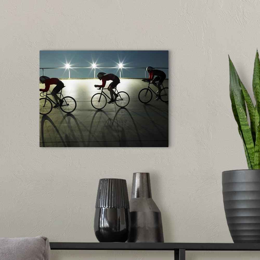 A modern room featuring Cyclists on velodrome track at night, side view