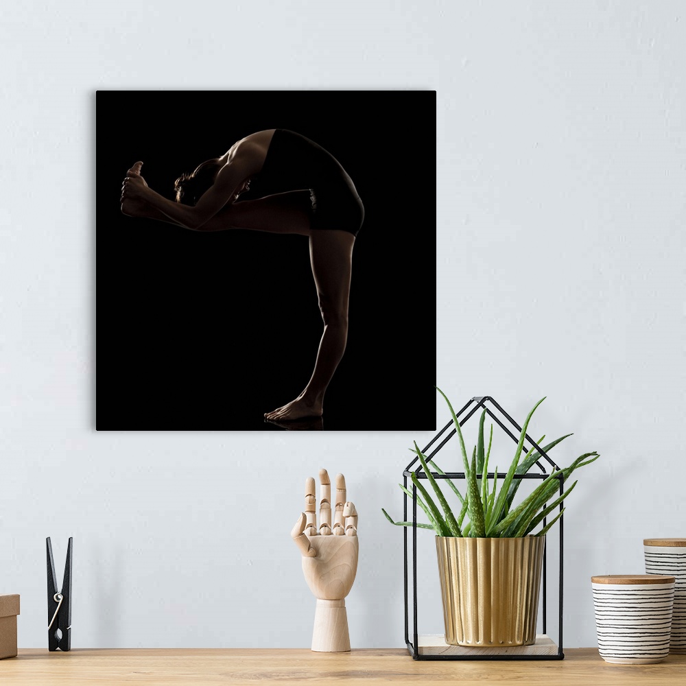 A bohemian room featuring Studio shot of young woman practicing yoga.  The standing head to knee pose, dandayamana janushir...