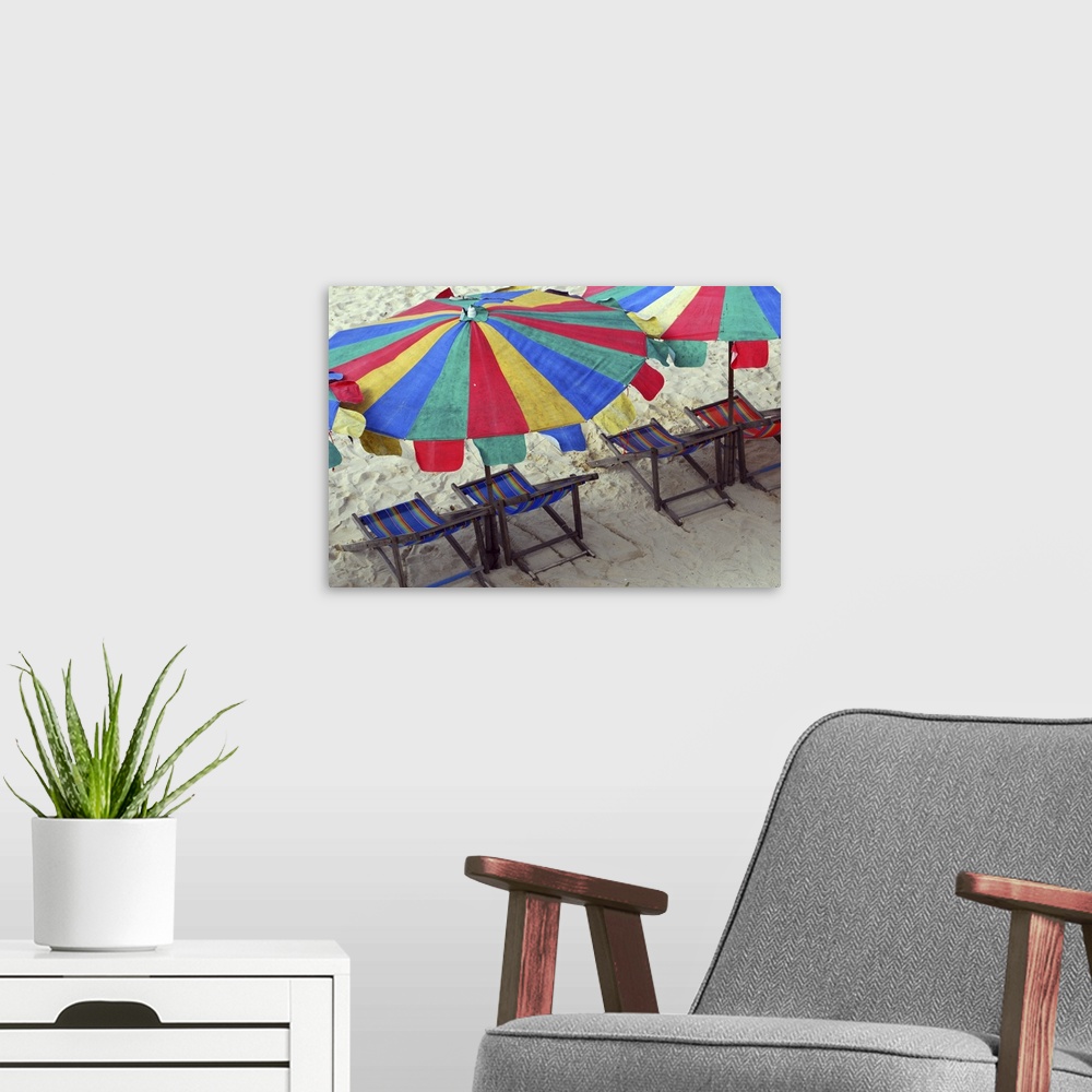 A modern room featuring Deck chairs and bright umbrellas on Sunny beach in Thailand.