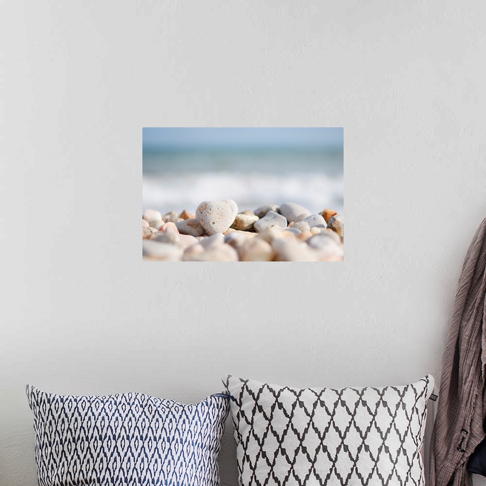 A bohemian room featuring Closeup photograph of a pile of stones on a beach in the foreground. The Mediterranean sea with w...