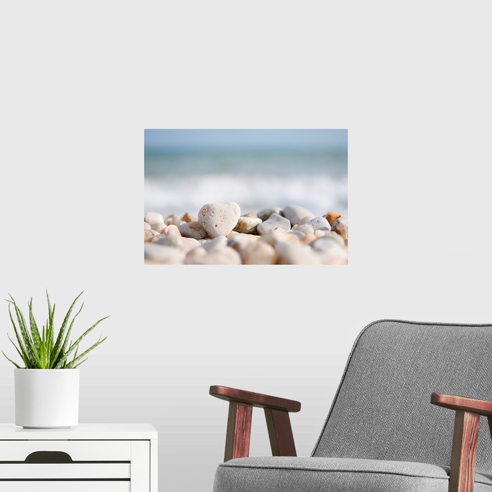 A modern room featuring Closeup photograph of a pile of stones on a beach in the foreground. The Mediterranean sea with w...