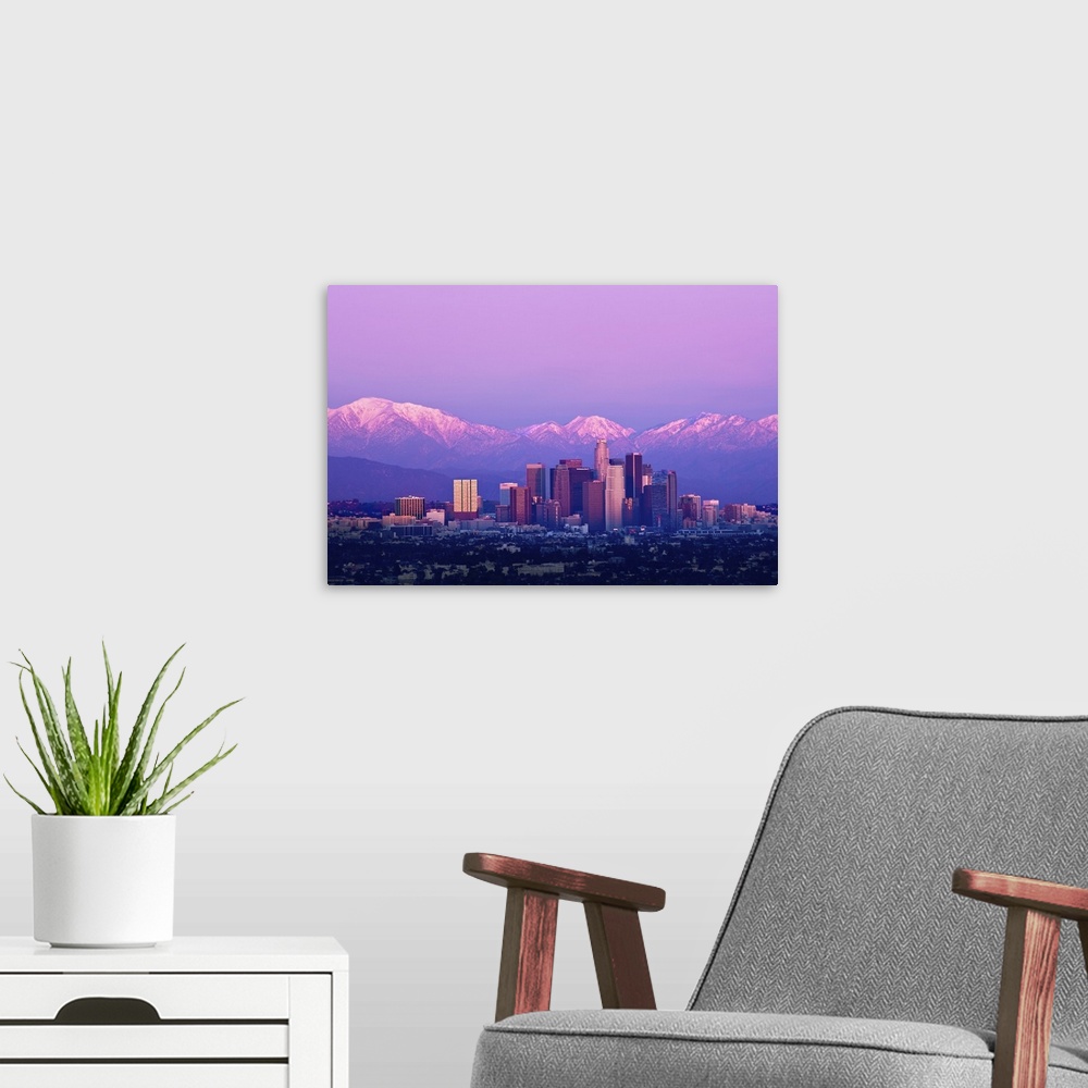 A modern room featuring Downtown Los Angeles and sunset. Buildings are lit from setting sun and mountains are capped with...