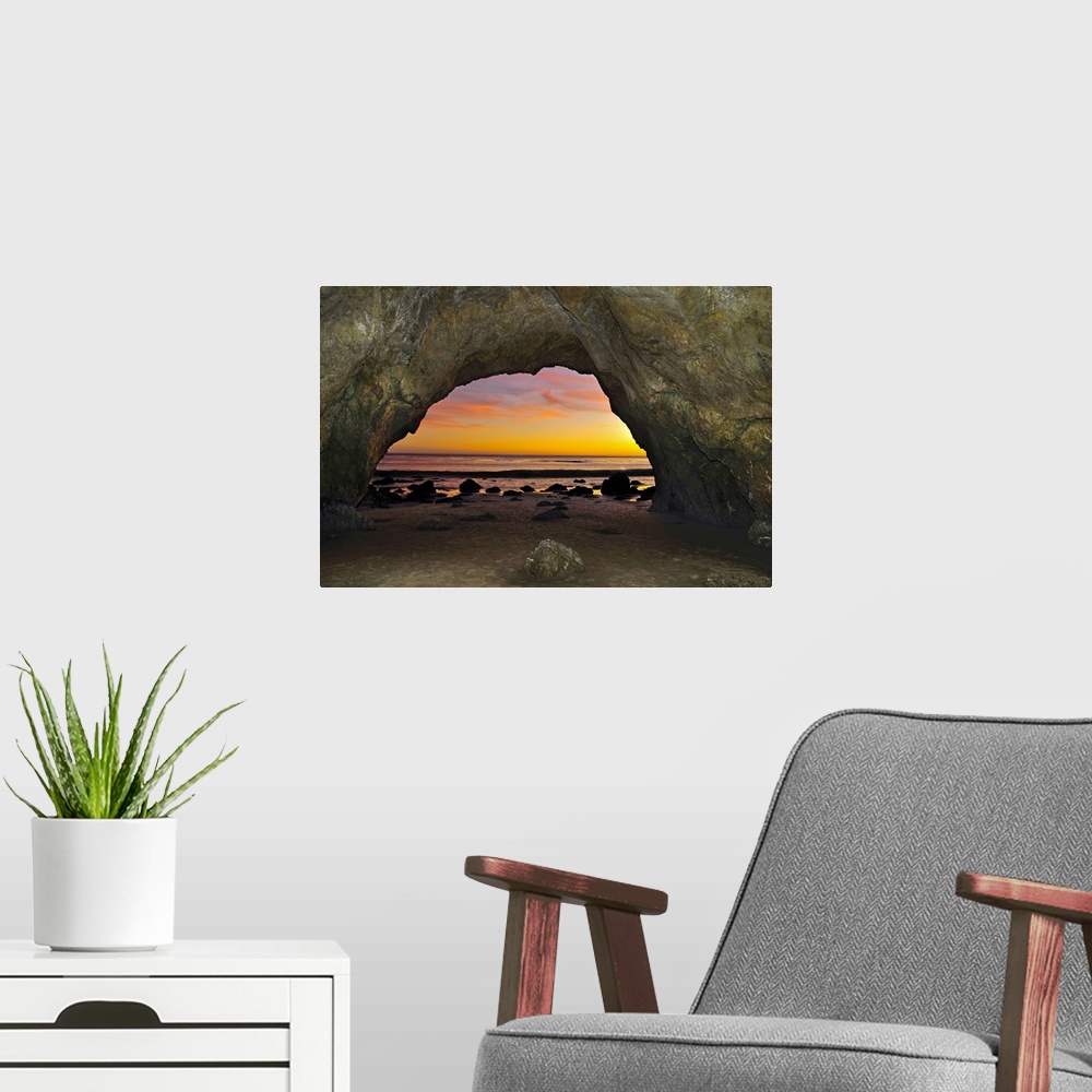 A modern room featuring Dramatic sunset seen from inside cave on beach.