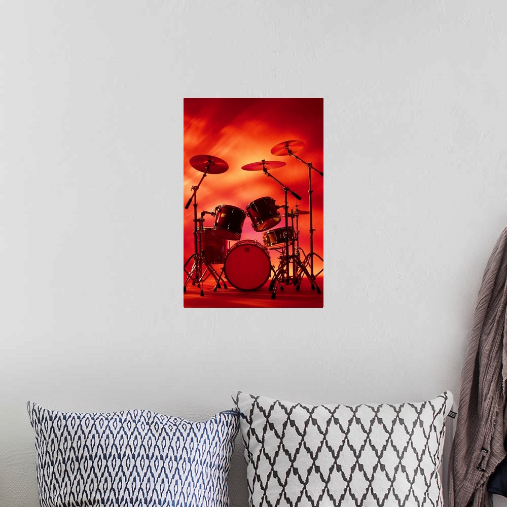 A bohemian room featuring Large vertical photograph of a drum set with symbols, surrounded by warm, fiery lighting.