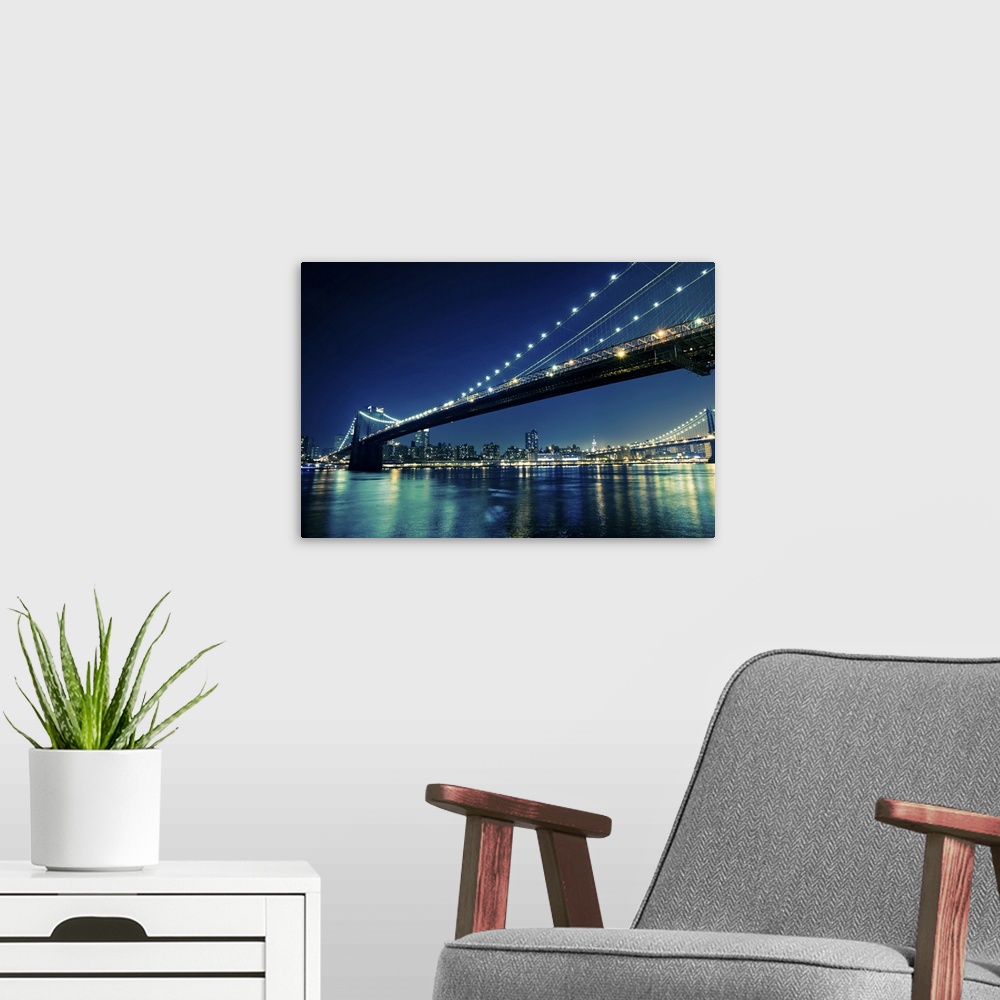 A modern room featuring The city of New York and bridges that stretch across the river are illuminated under a night sky ...
