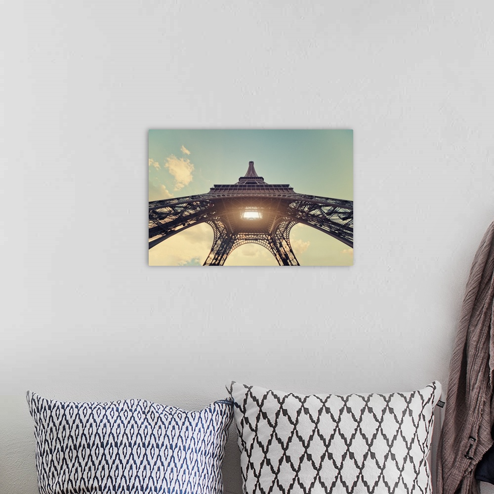 A bohemian room featuring Eiffel Tower with sun shining through center.