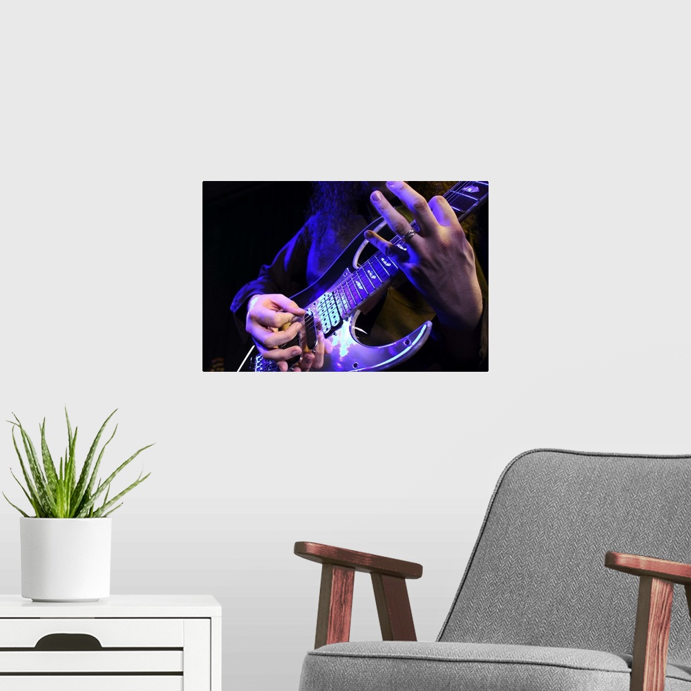 A modern room featuring close up shot of an electric guitar as it is played up on stage