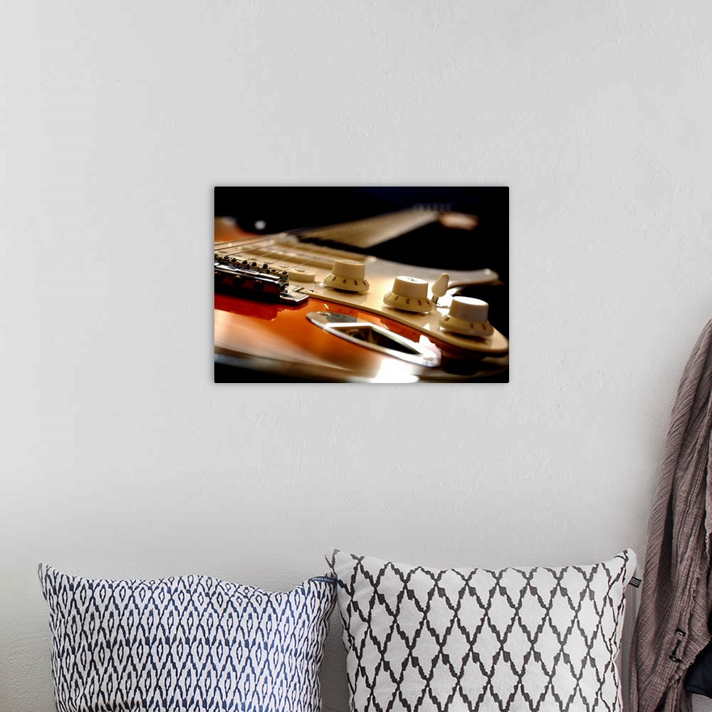A bohemian room featuring Up close view of an electric guitar seen from the bottom up on canvas.
