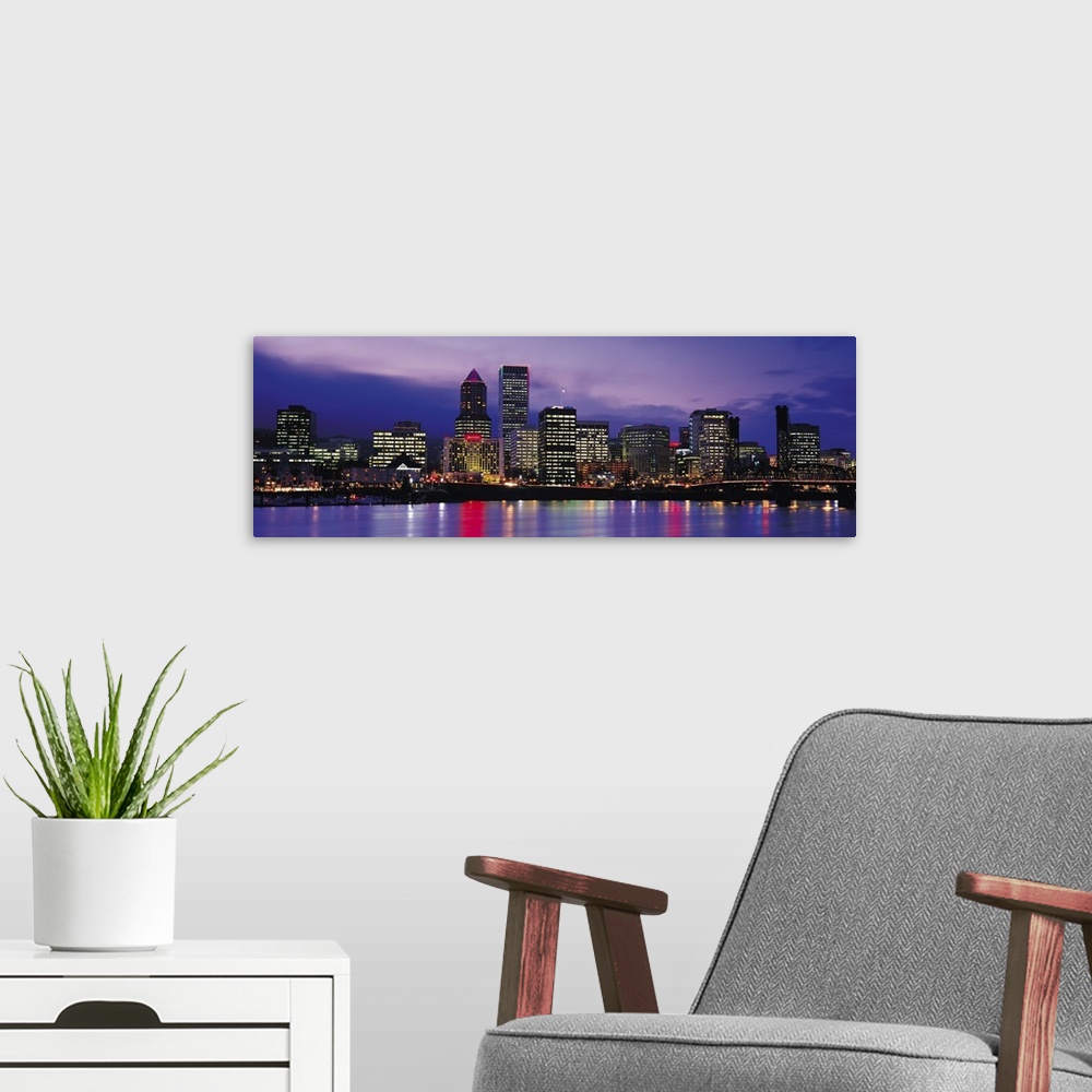 A modern room featuring Panoramic photograph on a big canvas of brightly lit buildings of the Portland skyline, reflectin...