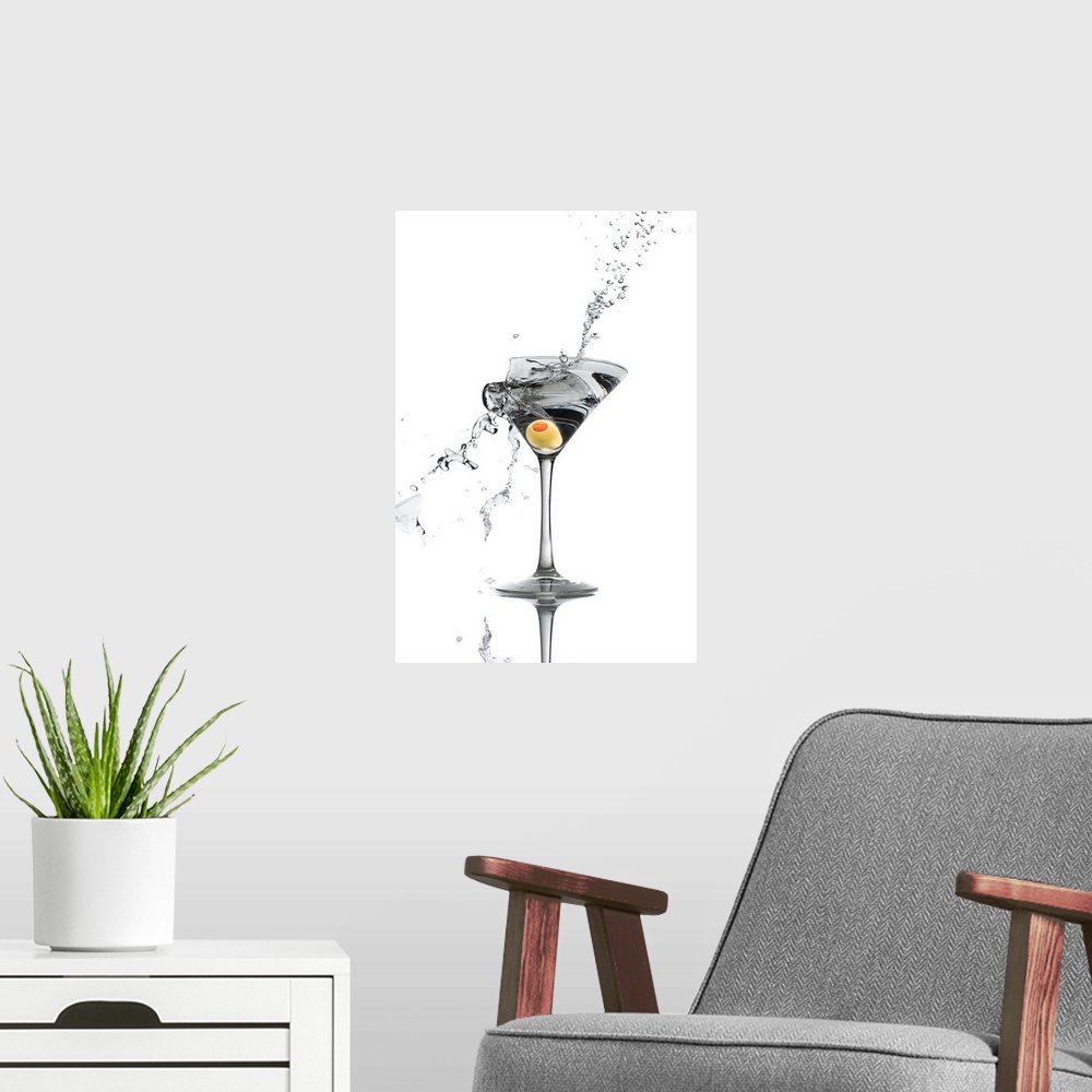 A modern room featuring A shattering martini glass on a white background spraying liquid outward.
