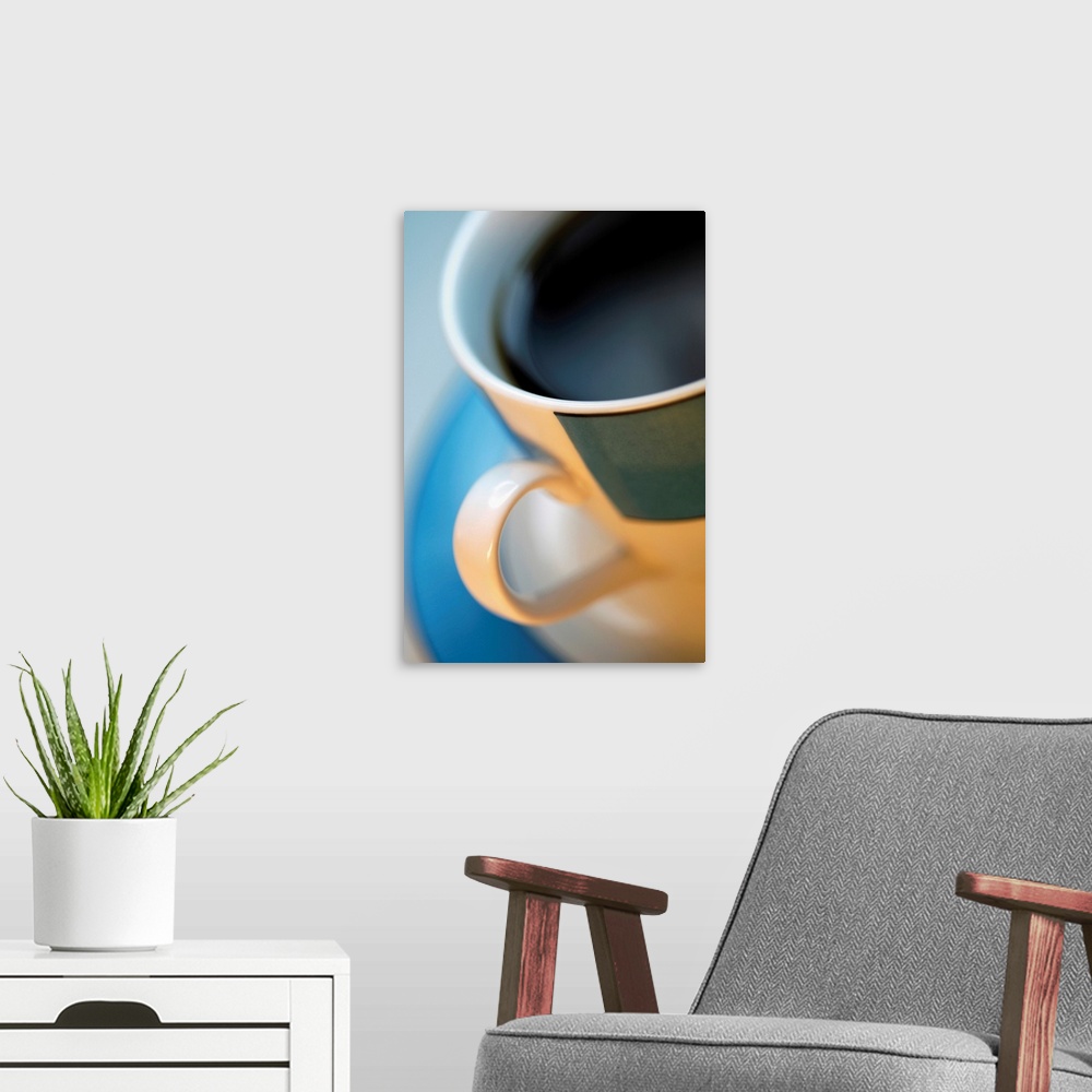 A modern room featuring Extreme close-up of cup of black coffee in tan and black cup with blue saucer