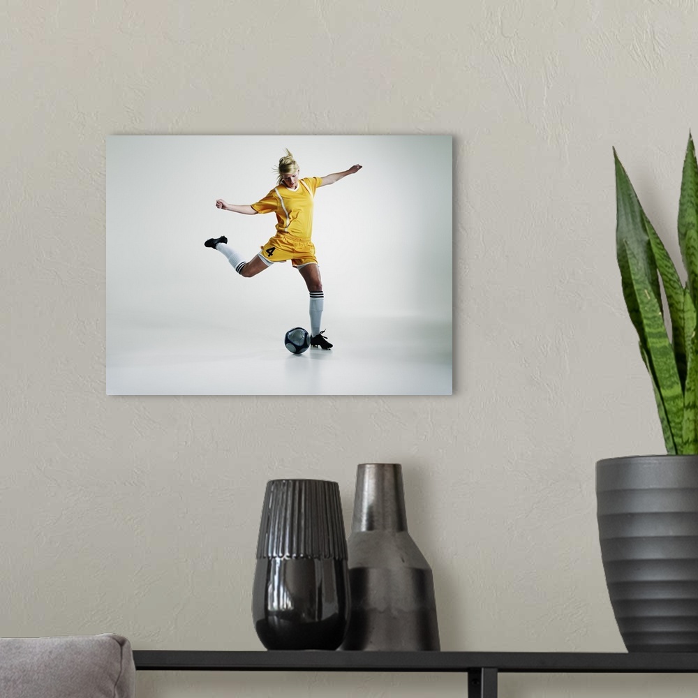 A modern room featuring Female soccer player preparing to kick soccer ball