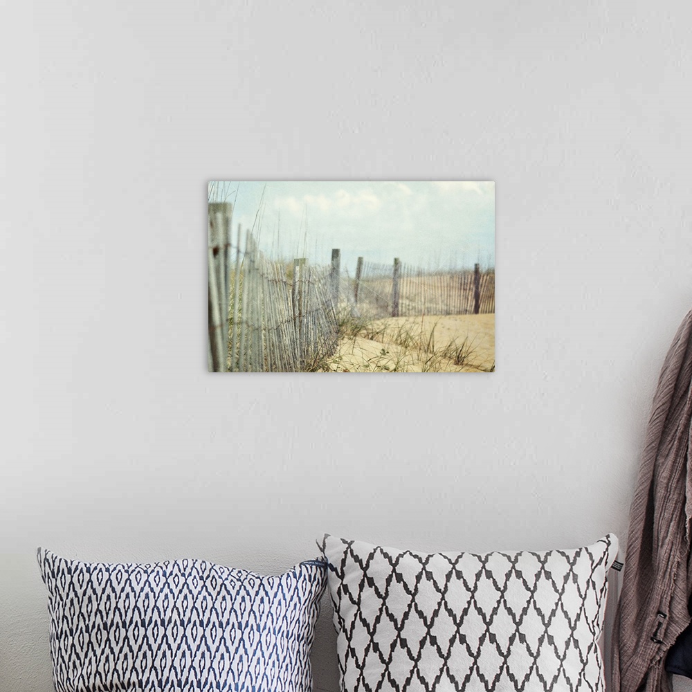 A bohemian room featuring Photograph of wooden fence and tall grass on hills of sand at the coast under cloudy skies.
