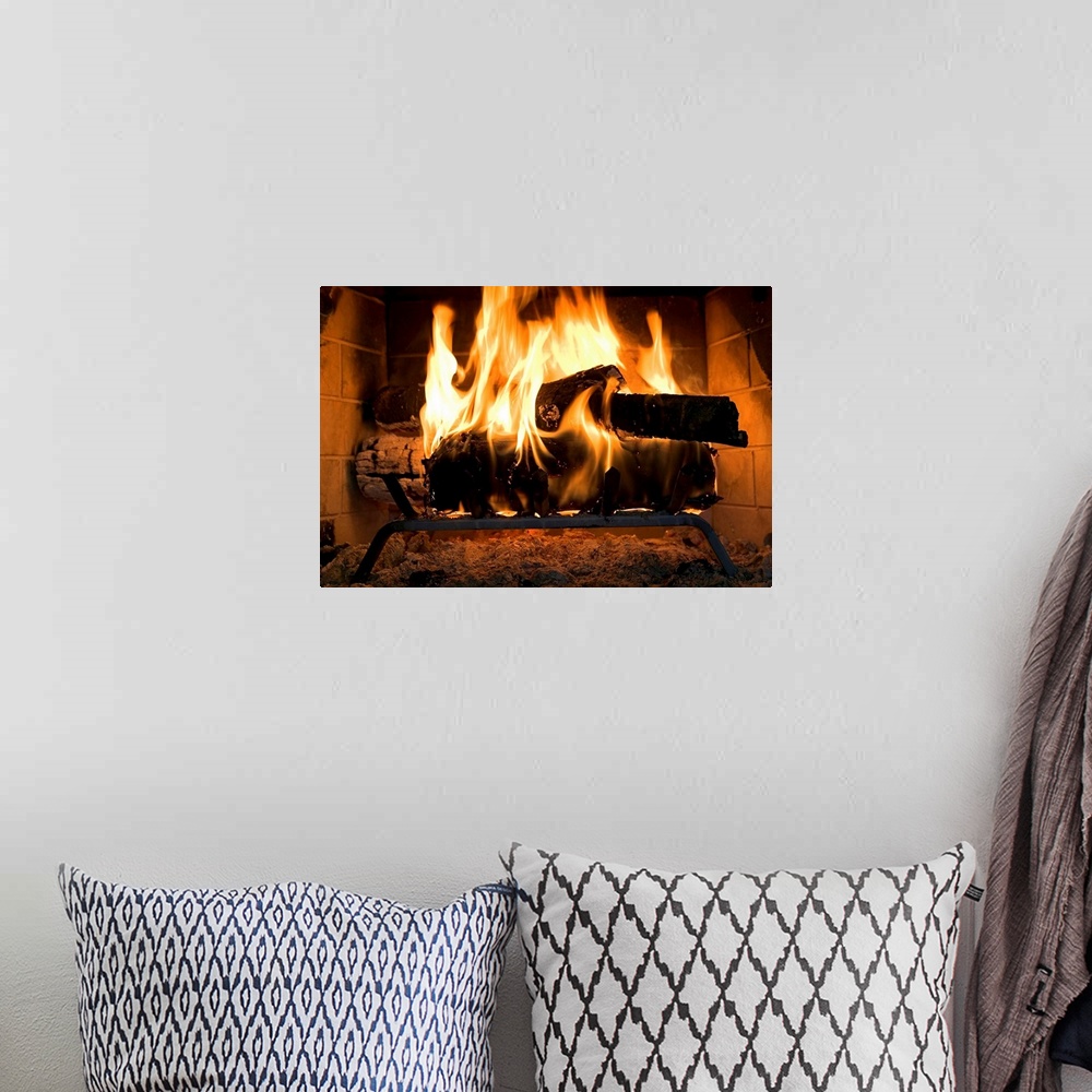 A bohemian room featuring A horizontal photograph of logs burning inside a personal, home fireplace lined with bricks