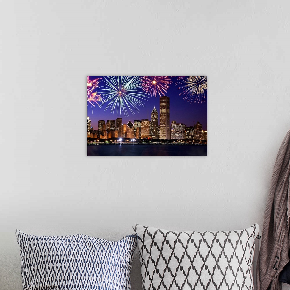 A bohemian room featuring Big photograph at nighttime includes bright pyrotechnics bursting above a row of tall skyscrapers...