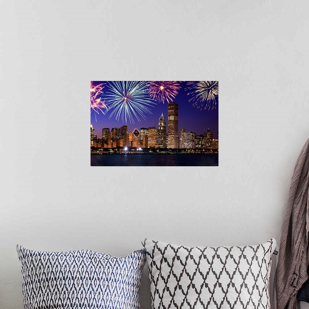 A bohemian room featuring Big photograph at nighttime includes bright pyrotechnics bursting above a row of tall skyscrapers...