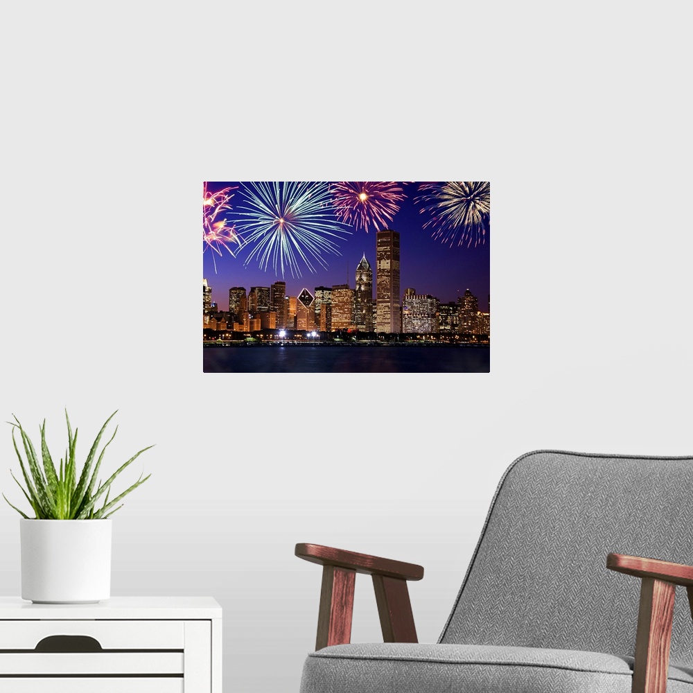 A modern room featuring Big photograph at nighttime includes bright pyrotechnics bursting above a row of tall skyscrapers...