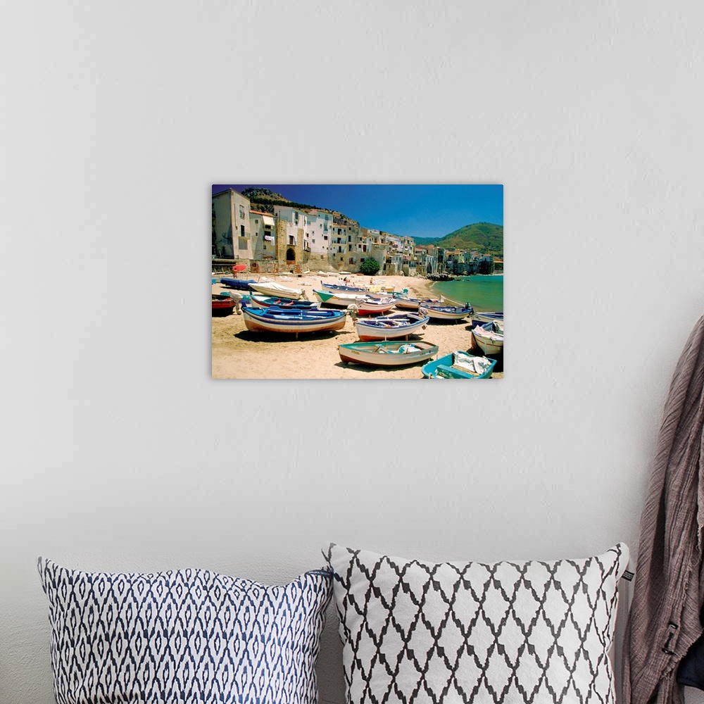 A bohemian room featuring Huge photograph showcases a fleet of small water vessels sitting on top of a sandy beach within t...