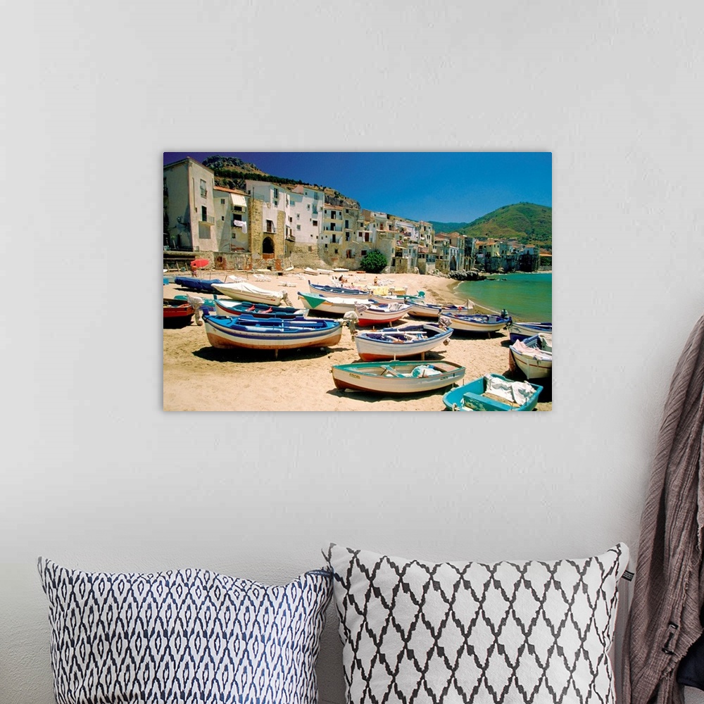 A bohemian room featuring Huge photograph showcases a fleet of small water vessels sitting on top of a sandy beach within t...