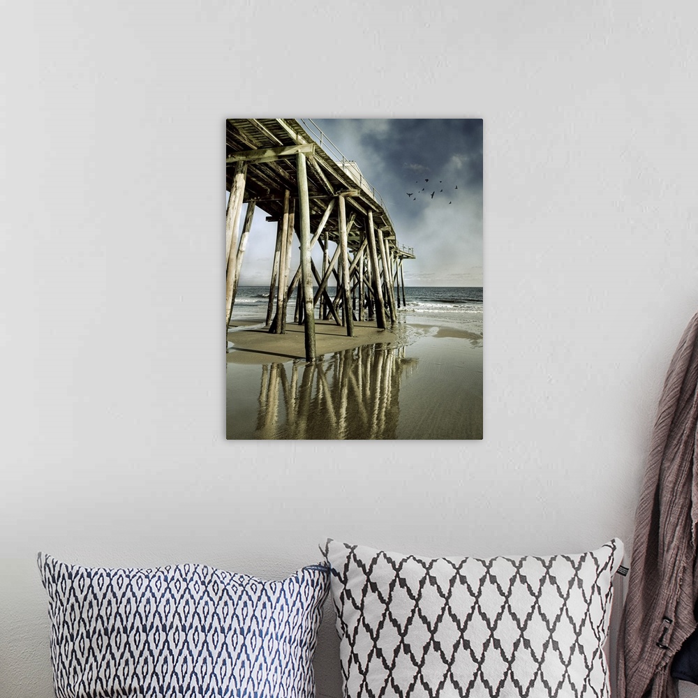A bohemian room featuring Fishing shack pier with reflection in sea and flock of birds in sky.