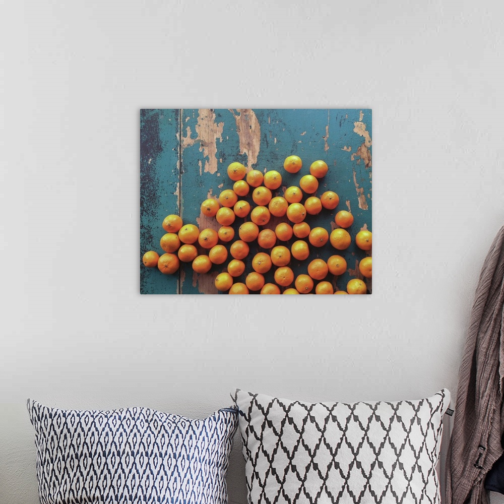 A bohemian room featuring Five pounds of clementine tangerines scattered on  wooden table with contrasting blue paint.