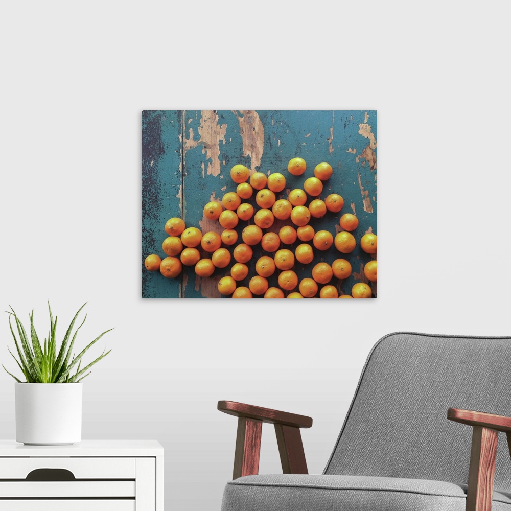 A modern room featuring Five pounds of clementine tangerines scattered on  wooden table with contrasting blue paint.