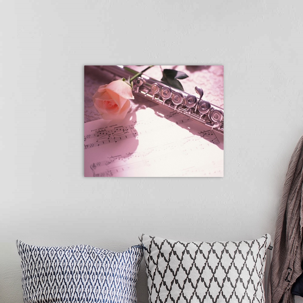 A bohemian room featuring Flute next to sheet music and pink rose