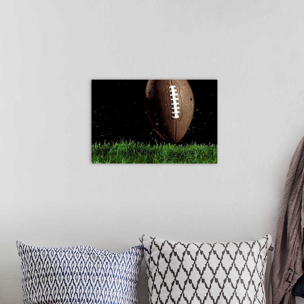 A bohemian room featuring Giant landscape photograph of a football in a vertical position as it moves above the wet grass w...