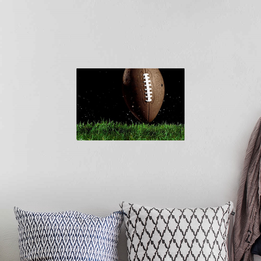 A bohemian room featuring Giant landscape photograph of a football in a vertical position as it moves above the wet grass w...