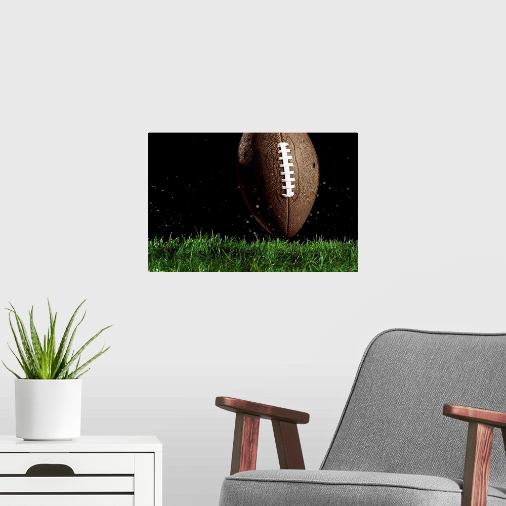 A modern room featuring Giant landscape photograph of a football in a vertical position as it moves above the wet grass w...