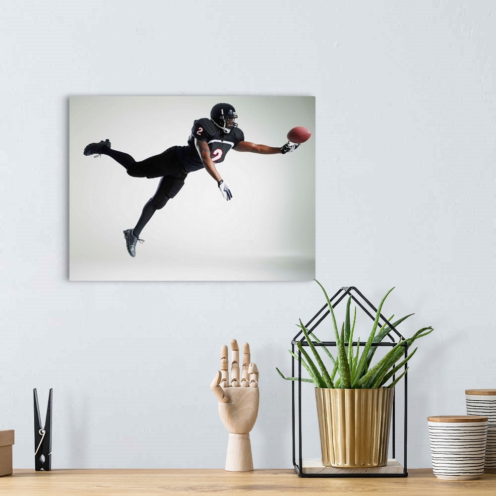 A bohemian room featuring Football player leaping in mid air to catch ball