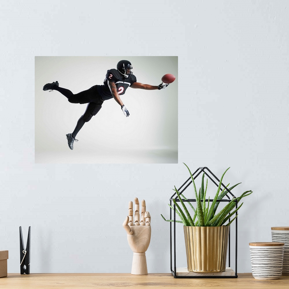 A bohemian room featuring Football player leaping in mid air to catch ball