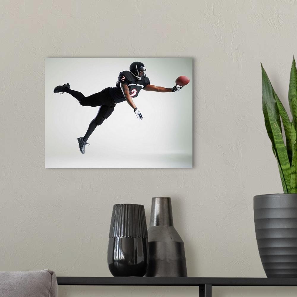 A modern room featuring Football player leaping in mid air to catch ball